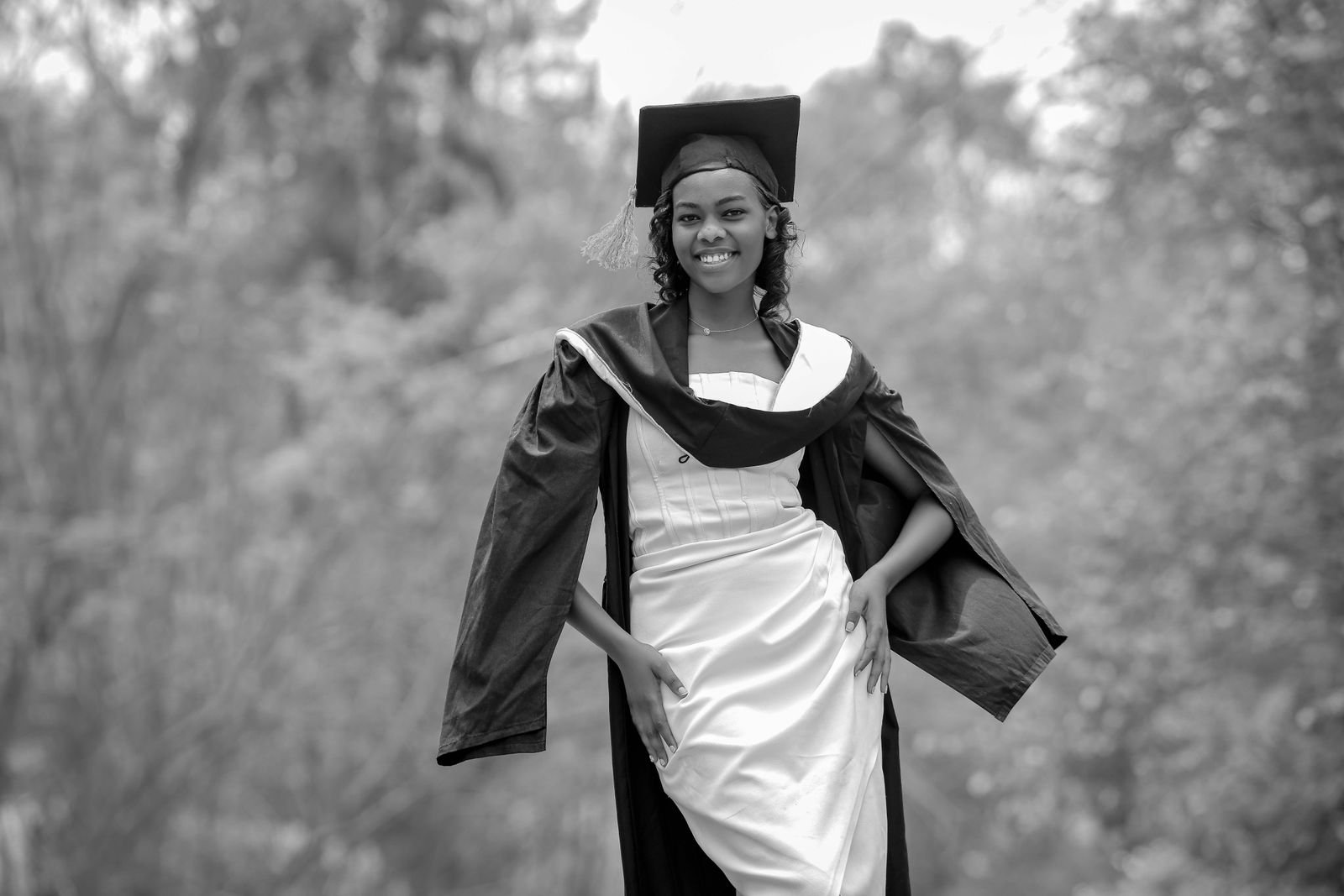 African graduate in cap and gown celebrating outdoors